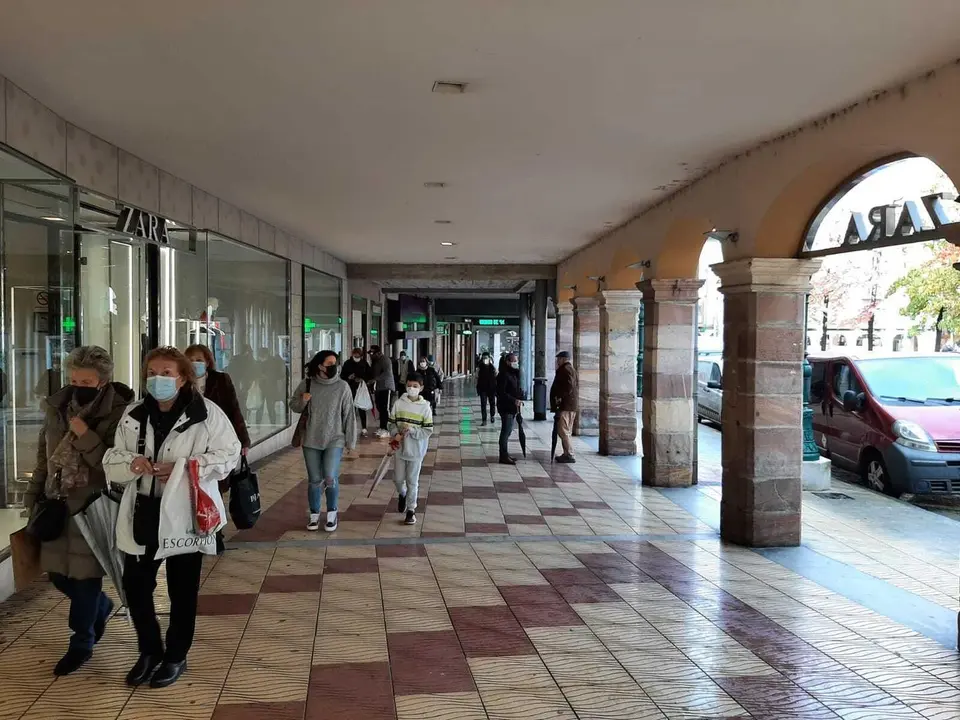 Varias personas pasan delante de la entrada de ZARA en Torralevega.