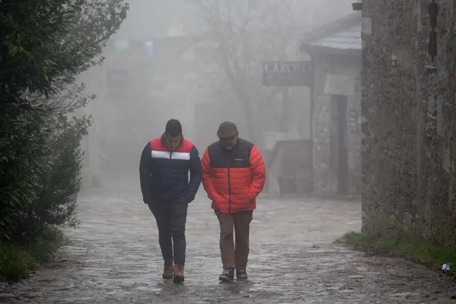 Dos hombres caminan entre la niebla en la aldea prerromana de O Cebreiro, Concello de Pedrafita do Cebreiro, Lugo, Galicia (Espa&ntilde;a).