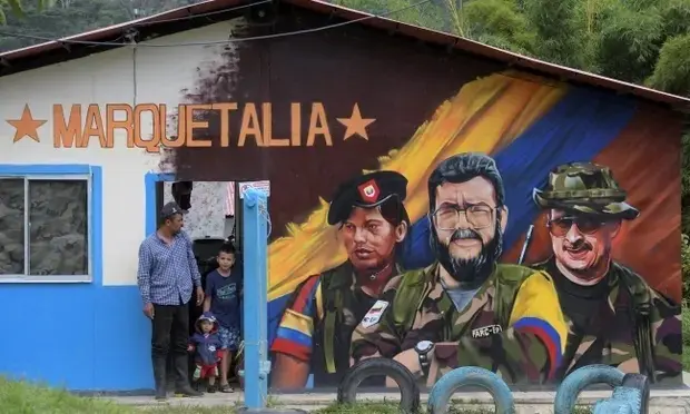 Un hombre y dos ni&ntilde;os junto a un mural del difunto comandante de las Farc Alfonso Cano, en el centro, en Colombia. Fotograf&iacute;a: Ra&uacute;l Arboleda / AFP / Getty Images