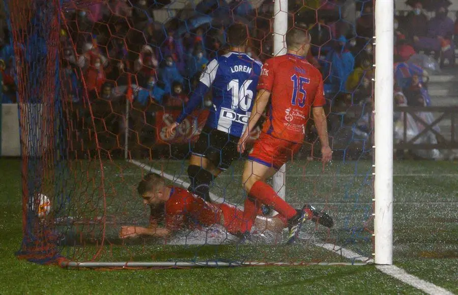 El jugador del Solares Medio Cudeyo, &Aacute;ngel Osl&eacute; (i), intenta que el bal&oacute;n no entre en la porter&iacute;a en el primer gol del Espanyol durante el partido de la la primera ronda de la Copa del Rey disputado este mi&eacute;rcoles en la localidad c&aacute;ntabra de Solares. EFE/Pedro Puente Hoyos