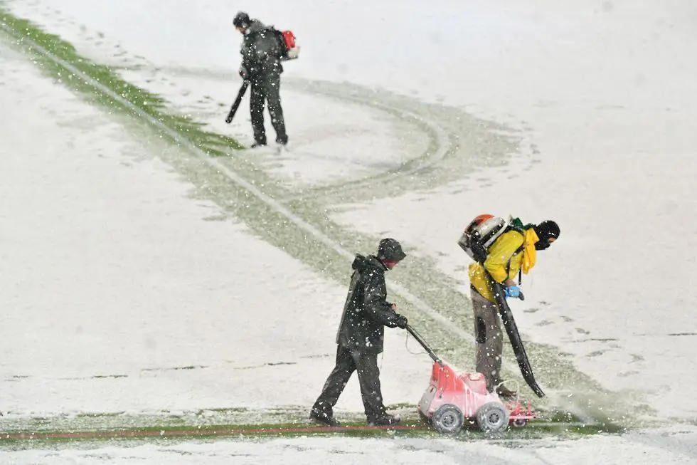 Empleados del Atalanta limpian las rayas del campo y las pintan de rojo para jugar con nieve.
ISABELLA BONOTTO (AFP)