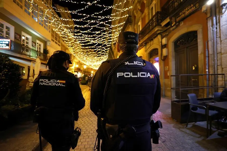 Dos agentes de la Polic&iacute;a Nacional patrullan por una c&eacute;ntrica calle de A Coru&ntilde;a, este martes. Galicia ha anunciado la puesta en marcha de un "toque de no queda", con la prohibici&oacute;n de estar por la calle entre las 2 y las 6 de la madrugada, excepto para desplazamientos individuales o de la misma unidad familiar, y restringe el horario de la hosteler&iacute;a a las 12 horas y del ocio nocturno a las 2 con car&aacute;cter general. EFE/ Cabalar