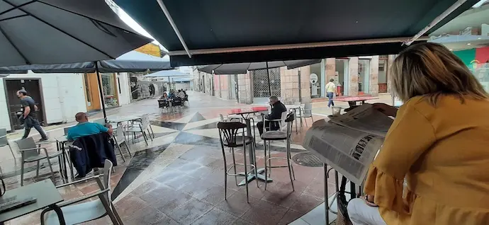 Una persona en un establecimiento de hosteler&iacute;a ojea las p&aacute;ginas del ALERTA en la calle Escalante de Torrelavega.