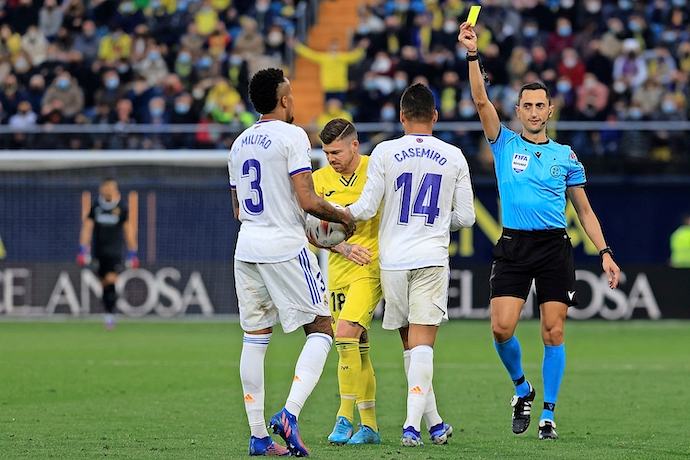 VILLARREAL, 12/02/2022.-El defensa del Real Madrid &Eacute;der Milit&atilde;o (i) recibe tarjeta amarilla, durante el partido de la jornada 24 de La Liga Santander hoy s&aacute;bado en el Estadio de la Cer&aacute;mica.- EFE / Domenech Castell&oacute;
