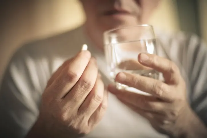 Senior man with pill. Focus is on hand. Close up.