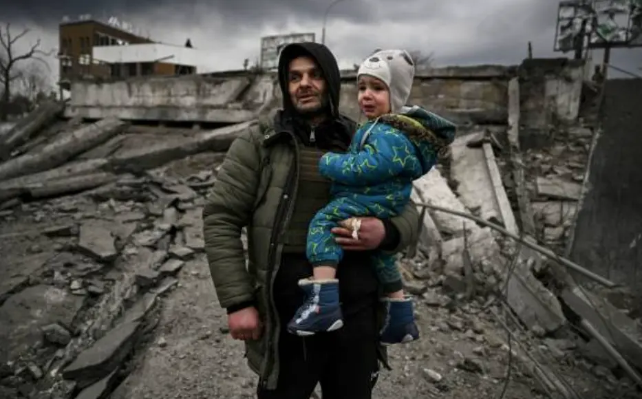 Un hombre sostiene a un ni&ntilde;o mientras huye de la ciudad de Irpin, al oeste de Kiev, el 7 de marzo de 2022. - Las fuerzas rusas bombardearon ciudades ucranianas desde el aire, la tierra y el mar el lunes, con advertencias de que se estaban preparando para un asalto a la capital, Kiev, mientras los civiles aterrorizados no lograron, por segundo d&iacute;a, escapar de la sitiada Mariupol. (Foto de ARIS MESSINIS / AFP)