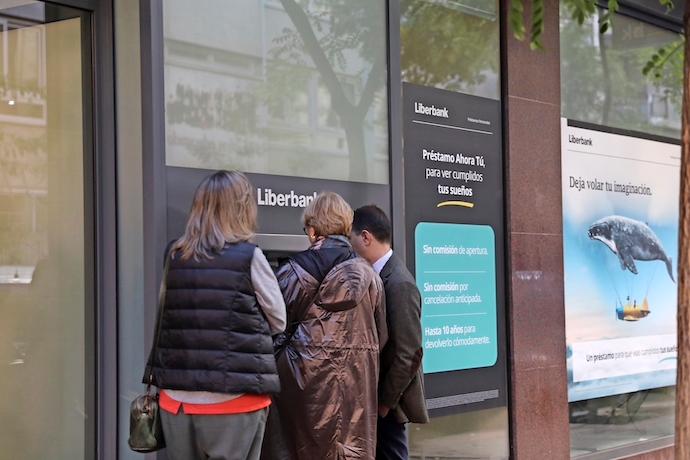 Tres personas efect&uacute;an una operaci&oacute;n en un cajero de una oficina de Liberbank.