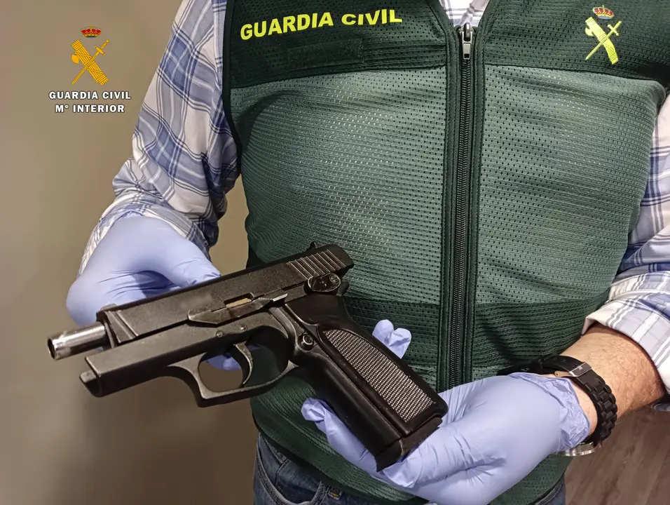 Un Guardia Civil sostiene la pistola incautada al detenido. / OPC