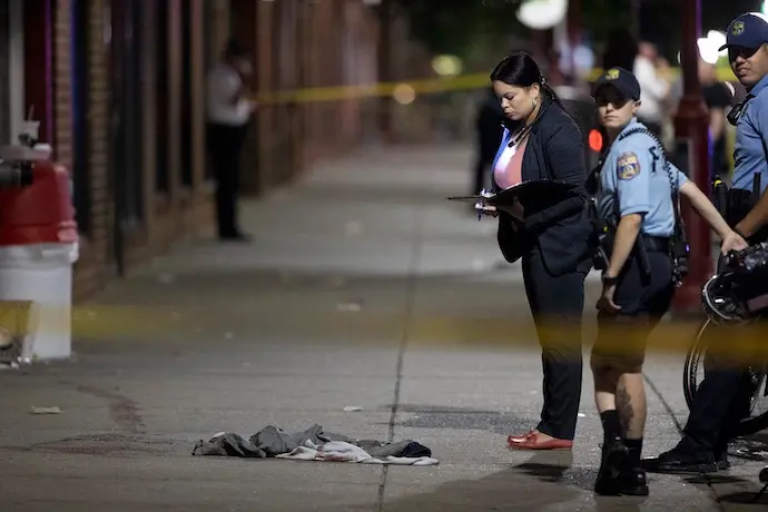 El polic&iacute;a de Filadelfia D. F. Pace examina las pruebas en el lugar de un tiroteo en South Street y sus alrededores que dej&oacute; 3 muertos y 11 heridos el 4 de junio de 2022.