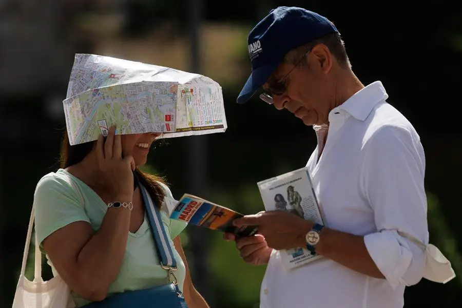Unos turistas se protegen del sol con un plano de Madrid este lunes mientras hace cola para entrar en el Palacio Real. La Agencia Estatal de Meteorolog&iacute;a (Aemet) prev&eacute; en algunos puntos de la regi&oacute;n temperaturas m&aacute;ximas de 41 grados cent&iacute;grados (&ordm;C) en las zonas sur, vegas y oeste de la regi&oacute;n, mientras que llegar&aacute; a los 39 &ordm;C en el &aacute;rea Metropolitana y el Henares y alcanzar&aacute; los 36 &ordm;C en la sierra. La Direcci&oacute;n General de Salud P&uacute;blica de la Comunidad de Madrid mantendr&aacute; hasta el jueves la alerta 2 o alto riesgo por calor. EFE/ Sergio P&eacute;rez