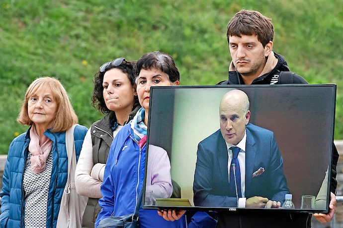 SANTIAGO DE COMPOSTELA, 13/10/2022.- Familiares de las v&iacute;ctimas muestran un video de Andr&eacute;s Cortabitarte, exjefe de Seguridad en la circulaci&oacute;n de Adif y segundo y &uacute;ltimo de los acusados por la muerte de 80 personas, este jueves, durante una nueva sesi&oacute;n del juicio por el accidente del Alvia, en la Ciudad de la Cultura de Santiago de Compostela. EFE/Lavandeira jr.
