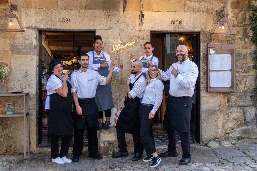 El equipo del restaurante Pasaje de los Nobles a la puerta del establecimiento mostrando el ne&oacute;n luminoso instalado con motivo de centenario, en manos de la cuarta generaci&oacute;n de la misma familia, una historia de la que habla con EFE Bel&eacute;n Morquillas, al frente ahora del restaurante.-EFE/Javier G. Paradelo