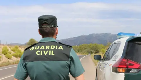 Un agente de la Guardia Civil junto a un veh&iacute;culo en una carretera. / E.P.