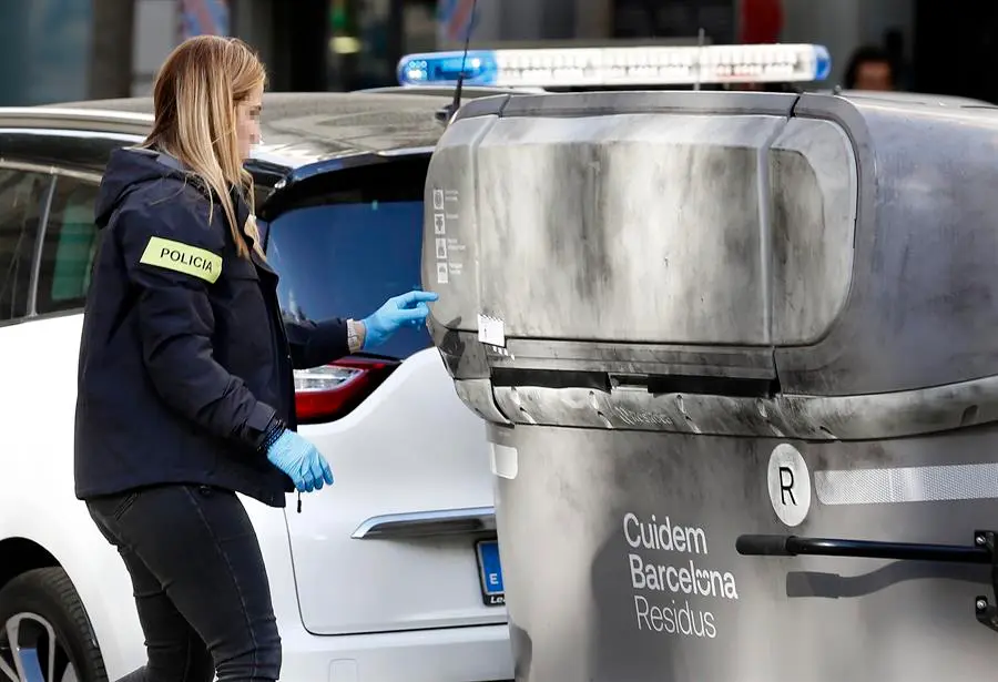 Una agente de los Mossos d'Esquadra realiza su trabajo en la calle Casanova con Avenida de Roma donde un vecino ha hallado el cad&aacute;ver mutilado de una persona dentro de una maleta en un contenedor (i). EFE / Andreu Dalmau