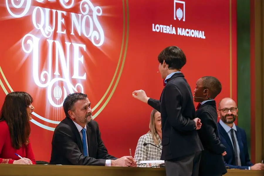 Los estudiantes de San Ildefonso Alonso D&aacute;valos Dur&aacute;n (3d) y su compa&ntilde;ero &Aacute;ngel Abaga Elebiyo (2d) cantan el premio Gordo durante el sorteo de Navidad en el Teatro Real en Madrid, este jueves. EFE/ Javier Liz&oacute;n