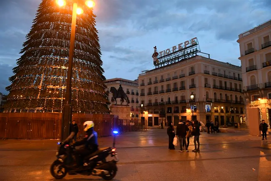 Un efectivo de la Polic&iacute;a Local pasa junto a un grupo de personas a primera hora de este domingo, 1 de enero de 2023. EFE / V&iacute;ctor Lerena