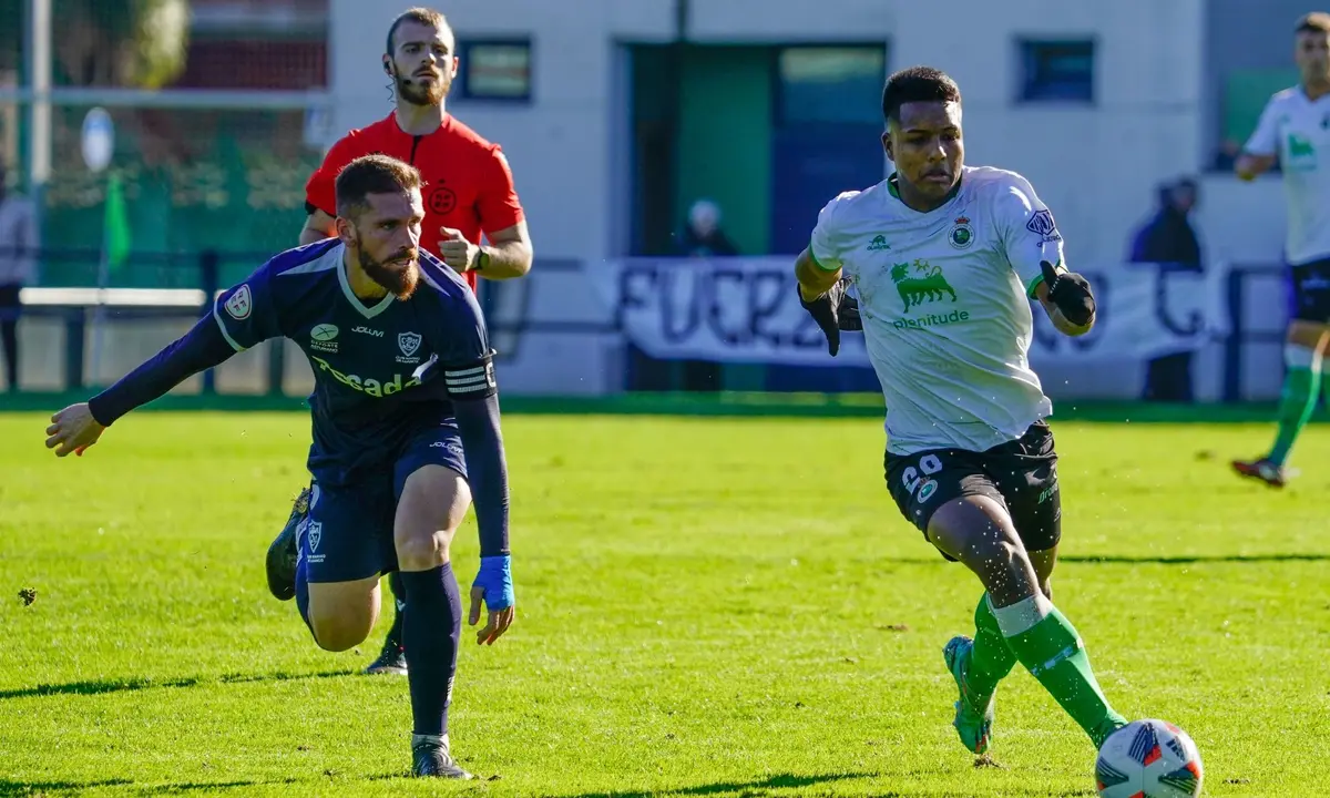 El futbolista del Rayo Cantabria conduce el bal&oacute;n, Jeremy, perseguido de un jugador del club Marino de Luanco