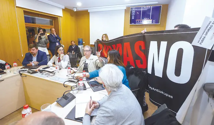 Una imagen del &uacute;ltimo pleno celebrado en el Ayuntamiento de Torrelavega, donde la presidenta del movimiento &lsquo;Meruelo sin okupas&rsquo; y coordinadora a nivel nacional de la plataforma &lsquo;Mi barrio seguro&rsquo;, Noem&iacute; Mu&ntilde;oz, detallaba los datos &laquo;abrumadores&raquo; de los casos en Torrelavega y Cantabria, que siguen en aumento. Sujetando el cartel al fondo, Elina Villegas. / ALERTA