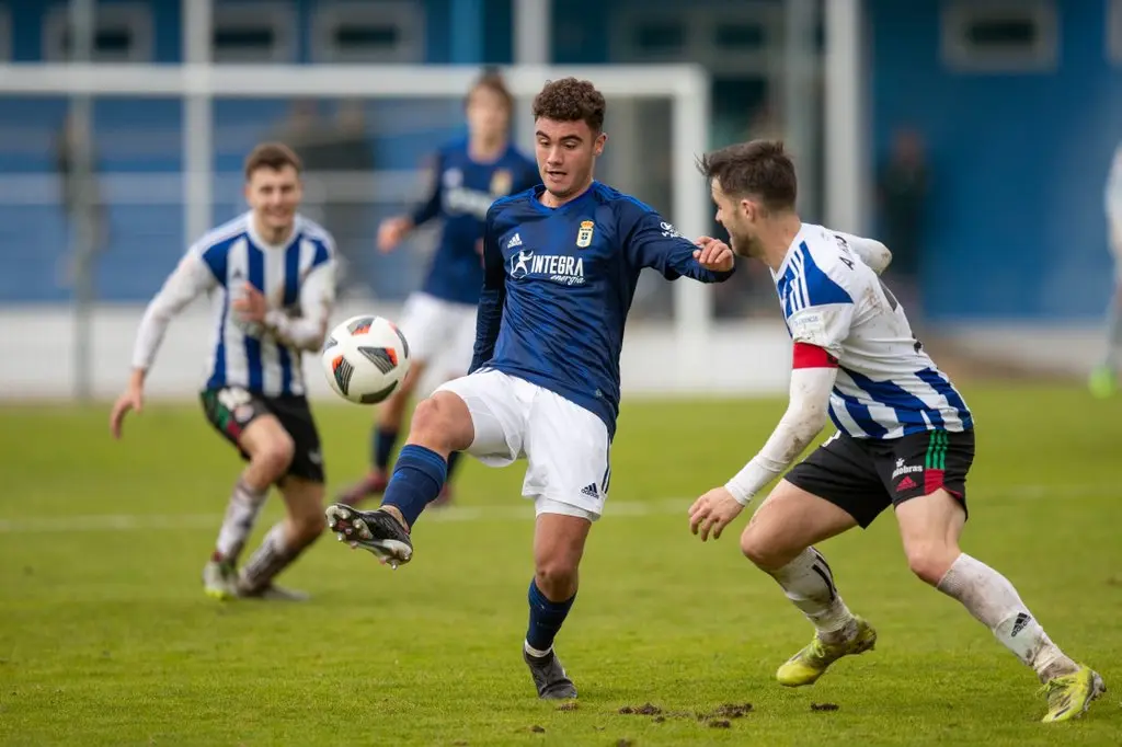 Un jugador del Oviedo controla el bal&oacute;n ante la presi&oacute;n gimn&aacute;stica.