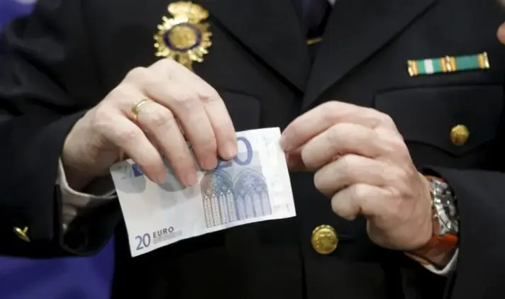 Un agente de Polic&iacute;a con un billete falso de 20 euros. EFE / &Aacute;ngel D&iacute;az