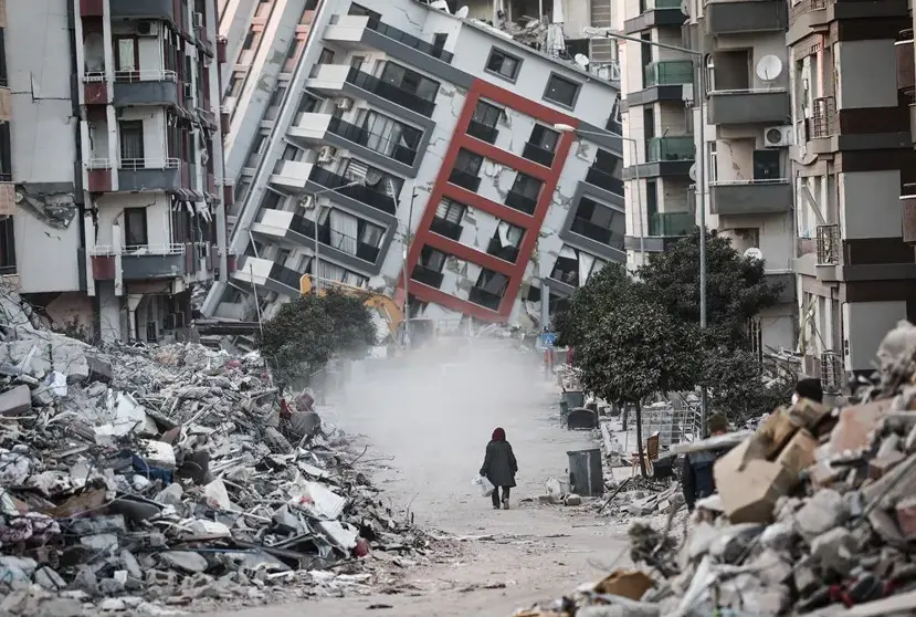 Una mujer pasa junto a edificios en ruinas, tras los terremotos de Turqu&iacute;a. EFE / Sedat Suna