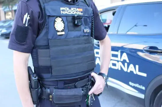 Agente de la Polic&iacute;a delante de un coche patrulla. / CNP