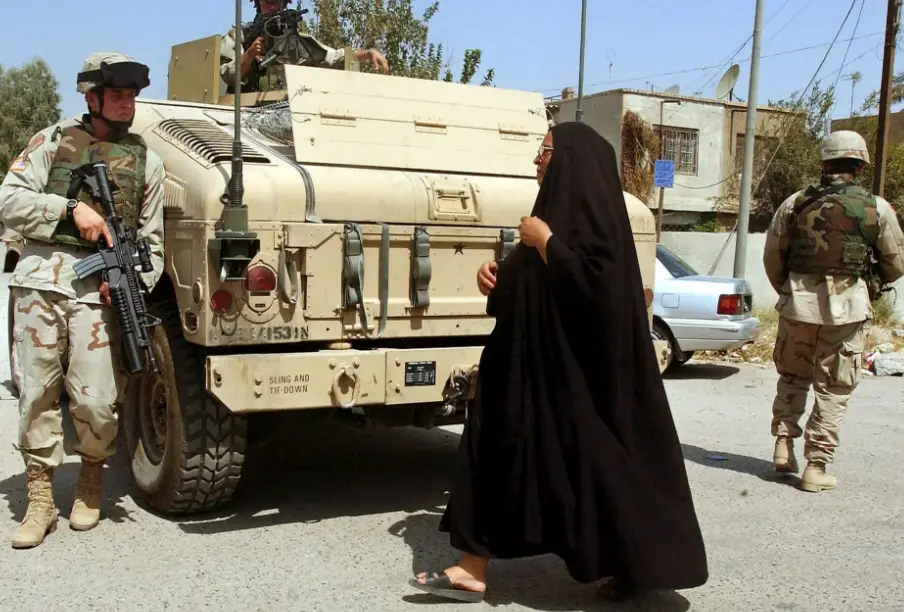 Fotograf&iacute;a fechada el 8 de septiembre de 2004 que muestra a una mujer iraqu&iacute; que se cruza con soldados estadounidenses que patrullan las calles de Bagdad (Irak). EFE/Mohammed Messara