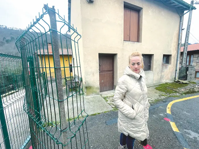Marta, vecina de Yermo al lado de la valla instalada delante de su entrada, y que impide el acceso rodado a su parcela. / ALERTA
