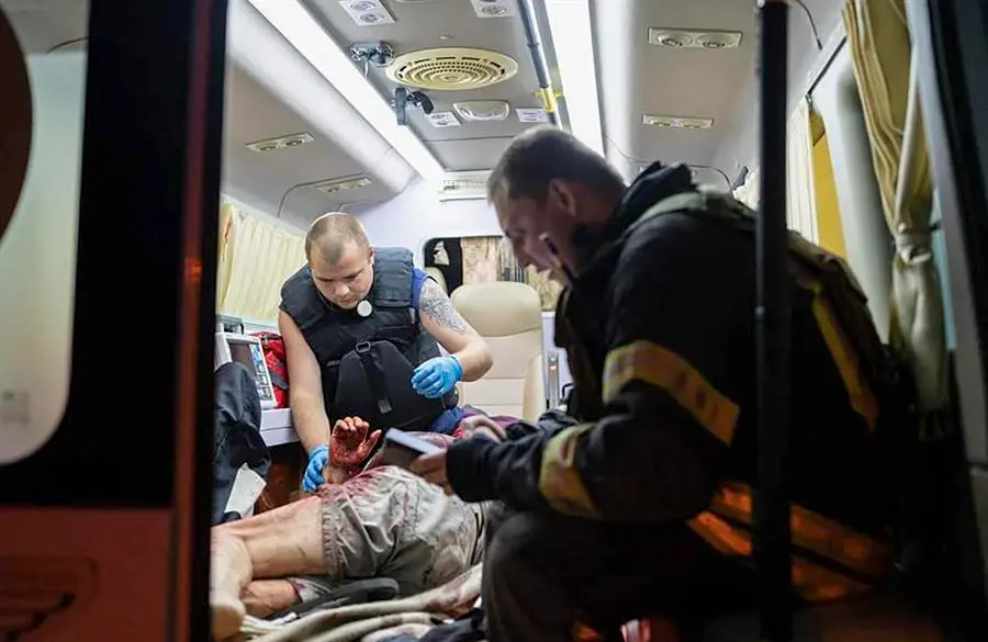 Trabajadores del Servicio Estatal de Emergencia (SES) de Ucrania atienden a una persona herida dentro de una ambulancia cerca de un edificio de apartamentos da&ntilde;ado despu&eacute;s de un ataque con drones en Kiev. EFE / STATE EMERGENCY SERVICE OF UKRAINE