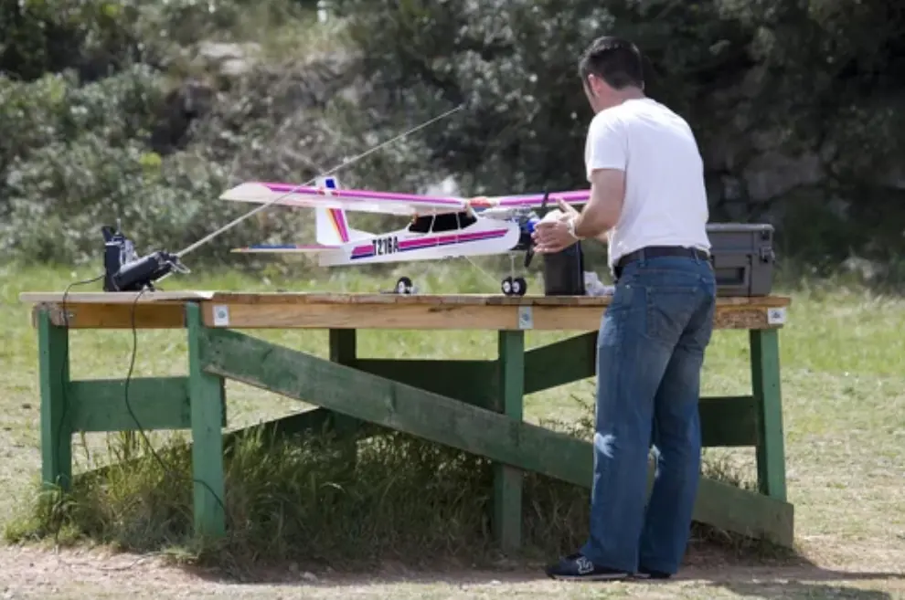 Un hombre junto a un avi&oacute;n de aeromodelismo.