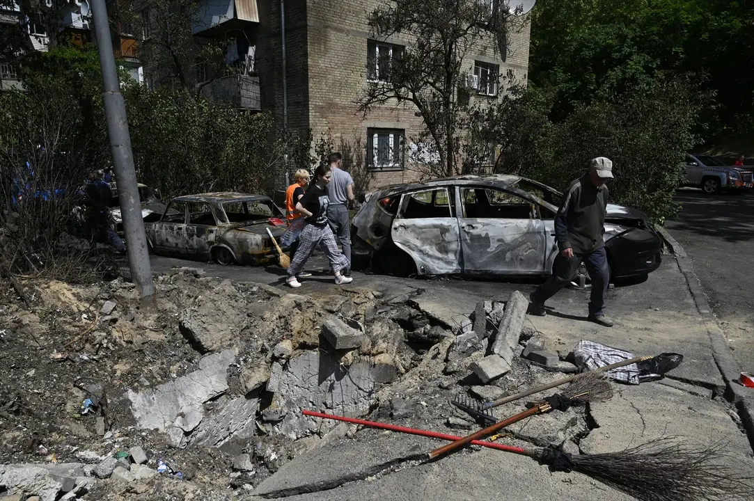 Unas personas caminan junto a dos coches destruidos por la guerra. EP / Sergei Chuzavkov