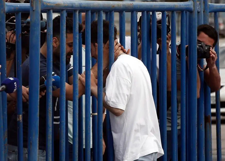 Fardi (i) de Siria, abraza a su hermano rescatado Mohamed (d), entre una valla en el puerto de Kalamata, Grecia. EFE / YANNIS KOLESIDIS