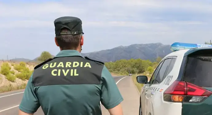 Un agente de la Guardia Civil junto a un veh&iacute;culo en una carretera. / GC