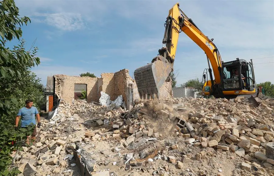 Vecinos trabajan para quitar los escombros de las estructuras destruidas por los bombardeos. EFE / SERGEY DOLZHENKO