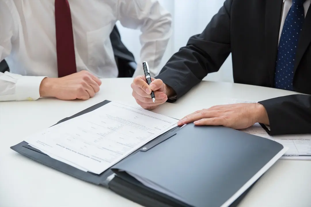 Dos personas firmando un documento. Pexels
