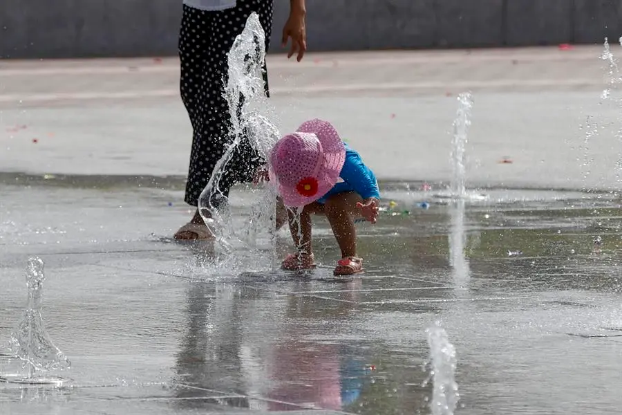 Una ni&ntilde;a se refresca en una fuente de chorros. / J.C. Hidalgo