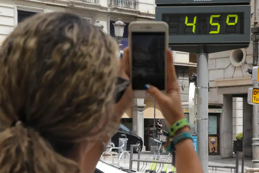 Una mujer fotograf&iacute;a la temperatura de un term&oacute;metro en Granada, este mi&eacute;rcoles. EFE / Pepe Torres.
