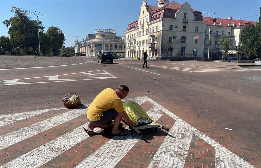 Foto cedida por el Servicio de Emergencia de Ucrania en la que aparece un hombre junto al cadaver de una de las v&iacute;ctimas del ataque ruso. EFE