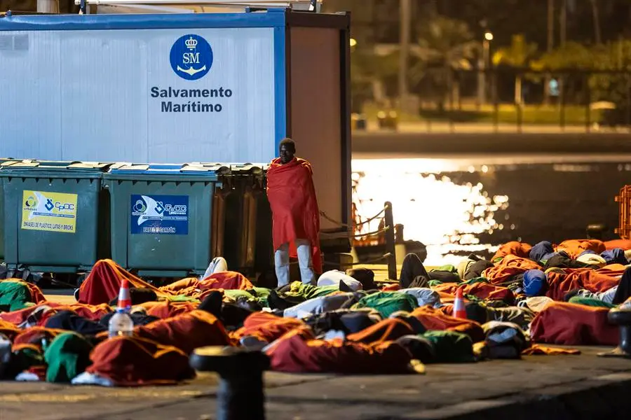 Unos 200 migrantes que llegaron en la tarde noche del viernes a Tenerife en dos cayucos han dormido en el muelle de Los Cristianos. EFE / Miguel Barreto