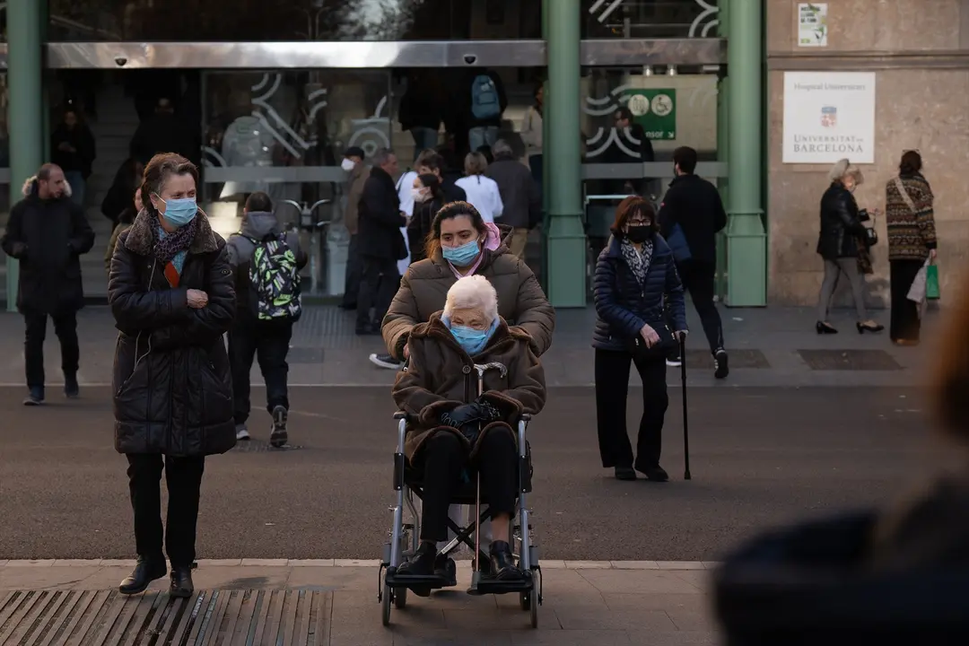 Varias personas con mascarillas en las afueras de un hospital. EP / David Zorrakino