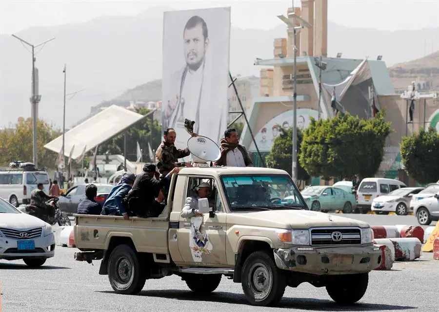 Simpatizantes hut&iacute;es viajan en un veh&iacute;culo pasando junto a una pancarta que representa al m&aacute;ximo l&iacute;der hut&iacute;, Abdul-Malik al-Houthi, en una calle de San&aacute;, Yemen. EFE / Yahya Arhab