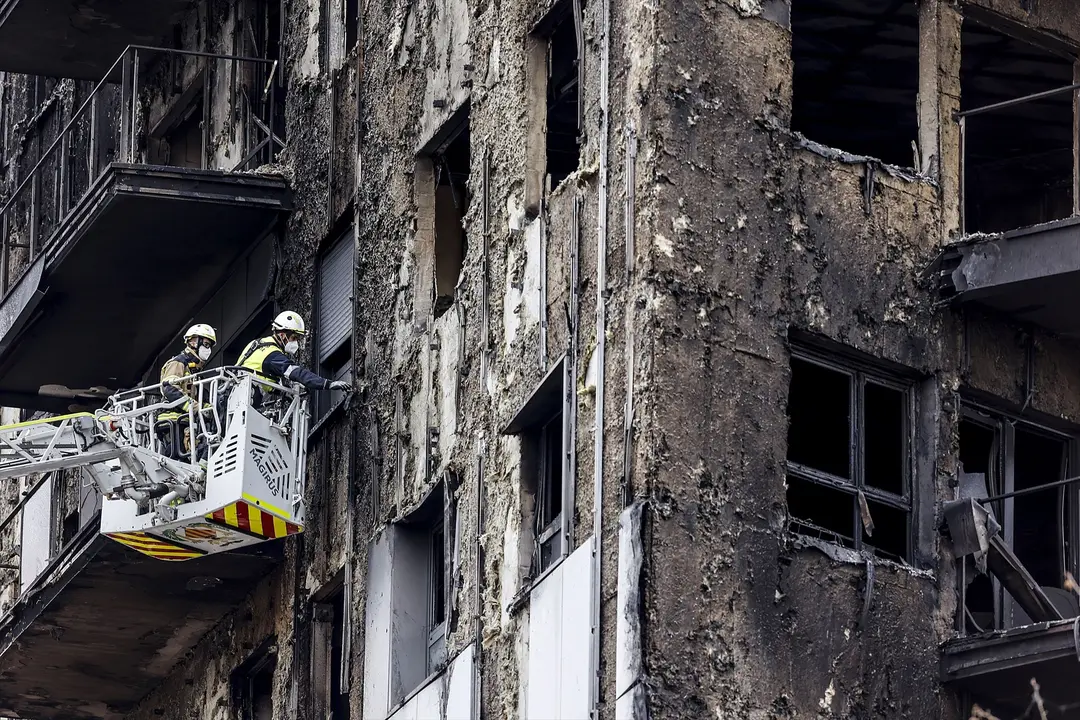Bomberos en una gr&uacute;a sanean la fachada quemada del edificio en Campanar. EP / Rober Solsona