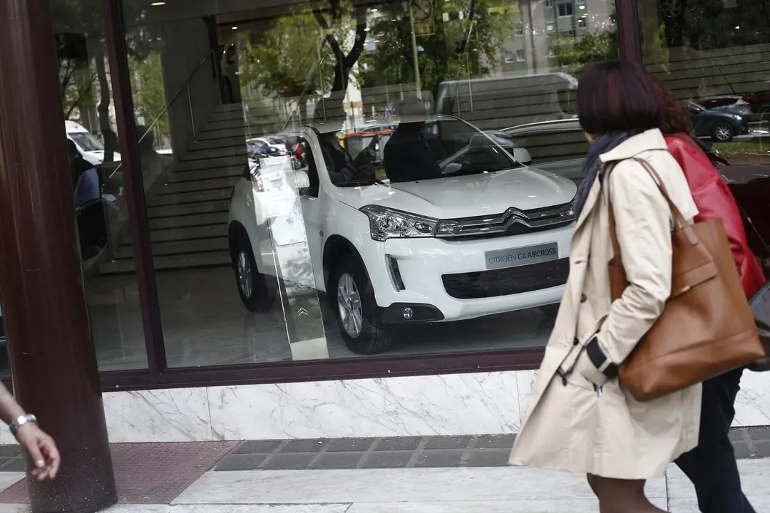 Una mujer caminando frente a un concesionario. EP / Archivo