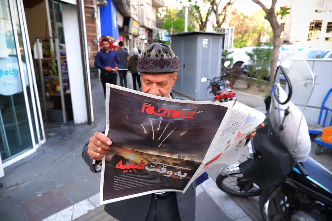 Un hombre en Teher&aacute;n leyendo un peri&oacute;dico con la imagen de unos ataques. EP / Rouzbeh Fouladi