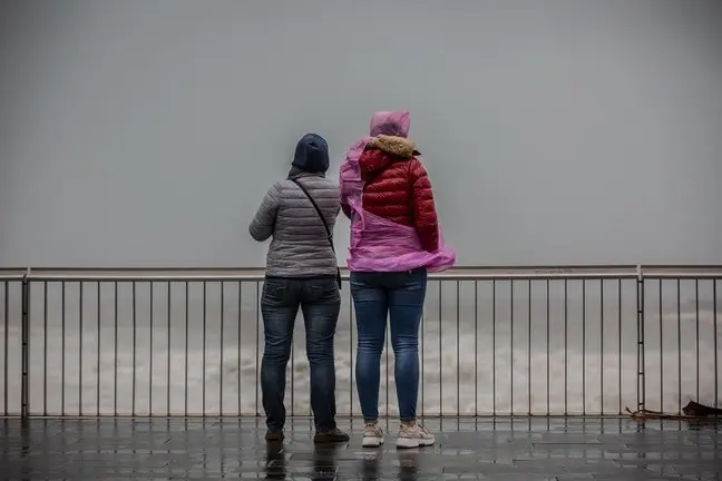 Dos mujeres en el paseo mar&iacute;timo durante un episodio de lluvias. / EP