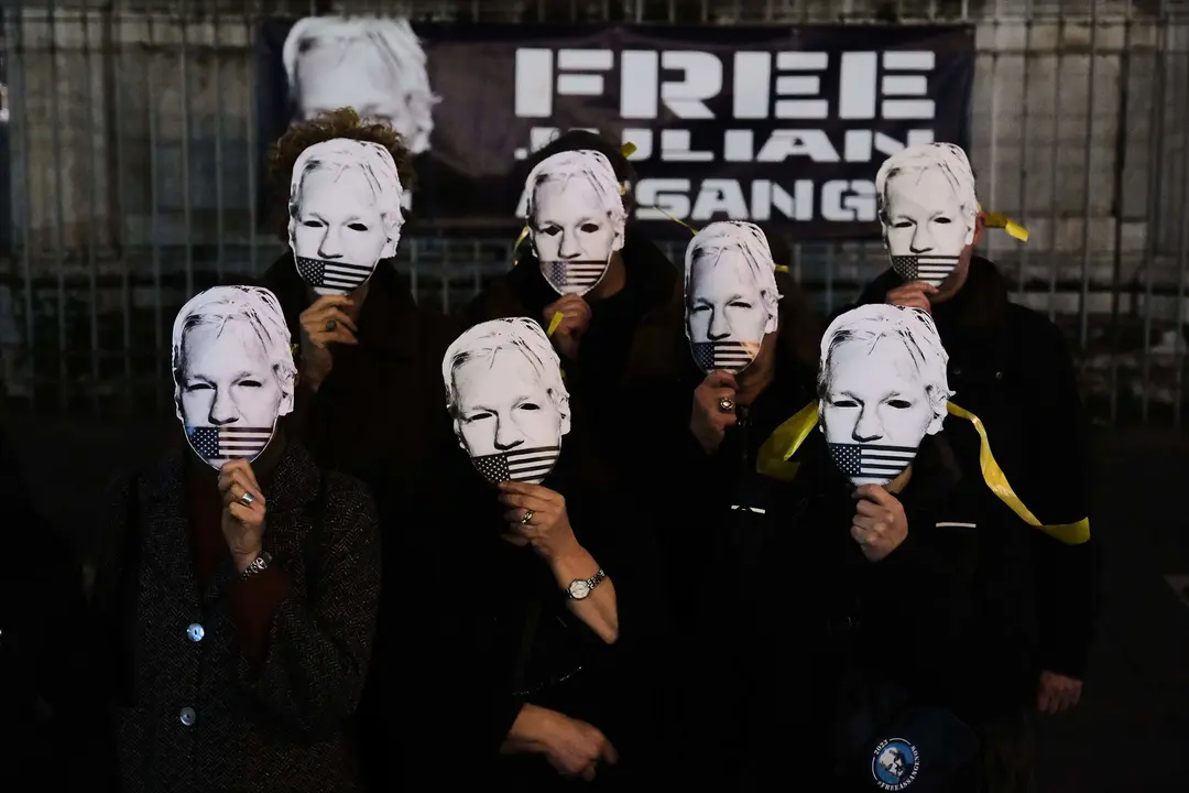 Varias personas con una m&aacute;scara con la cara de Julian Assange. / Antonio Balasco / Archivo