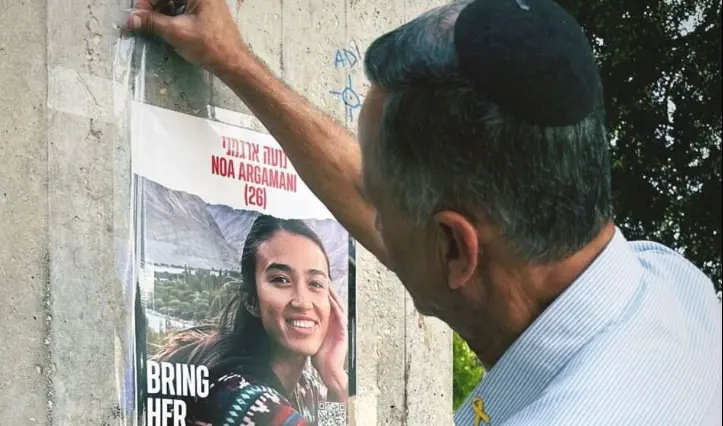 Un padre pega un cartel de su hija raptada por los terroristas de Ham&aacute;s.