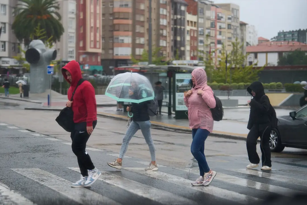 Varias personas se cubren de la lluvia y el viento con paraguas. EP