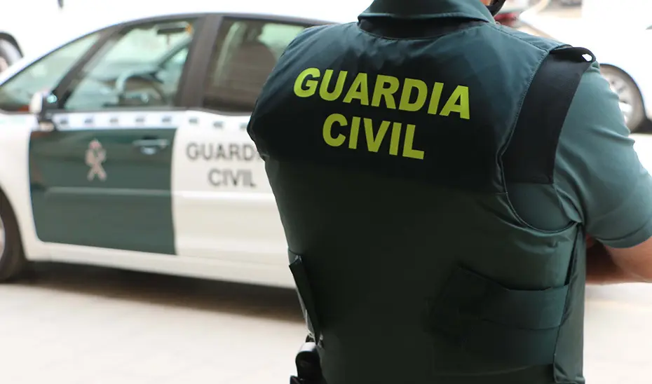 Un agente de la Guardia Civil, de espaldas, junto a un veh&iacute;culo oficial. / G.C.