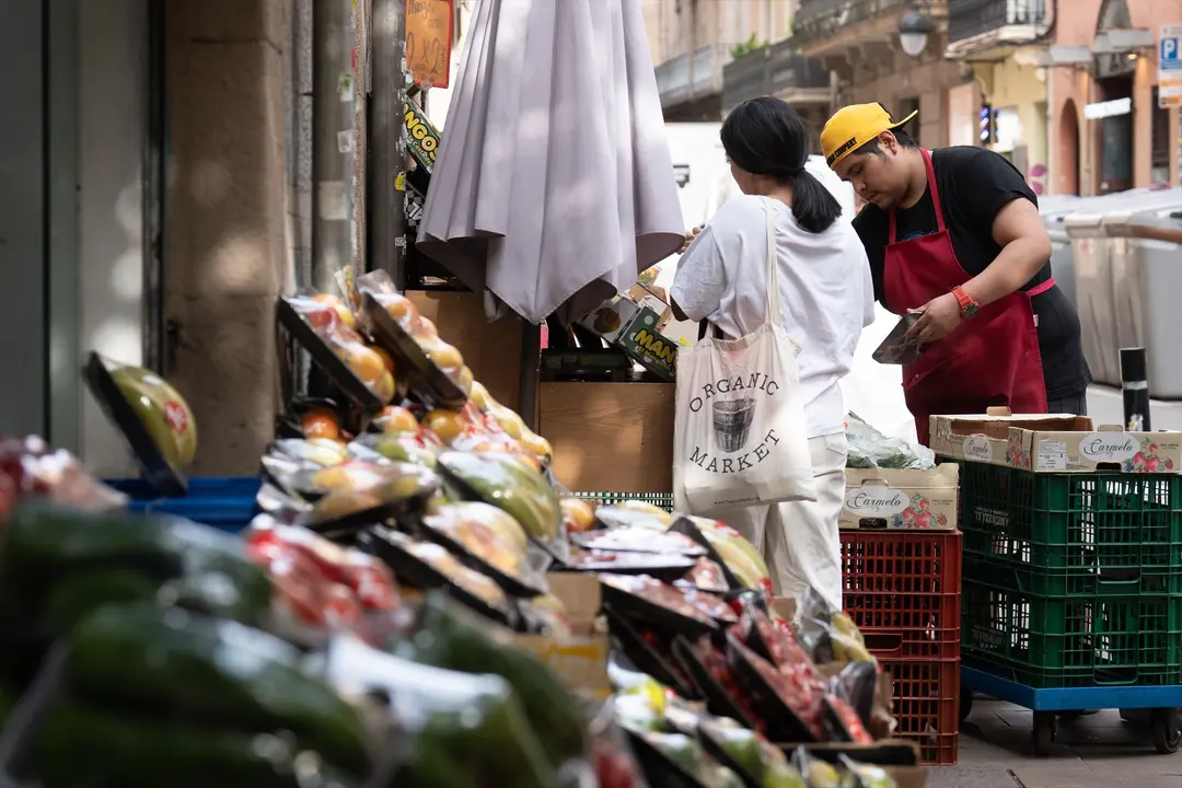 Varias frutas expuestas en el exterior de una fruter&iacute;a mientras un dependiente atiende a un cliente. /  David Zorrakino